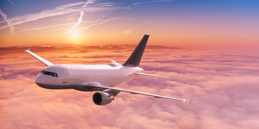 commercial airplane jetliner flying above dramatic clouds.